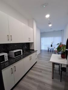 a kitchen with white cabinets and a dining room with a table at Albergue Adventus in Padrón