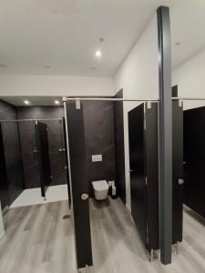 a bathroom with a toilet and black stalls at Albergue Adventus in Padrón