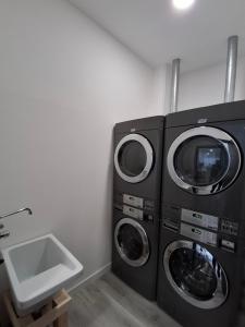 a laundry room with two washing machines and a sink at Albergue Adventus in Padrón