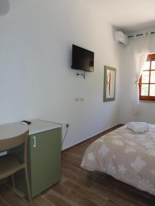 a bedroom with a bed and a desk and a television at B&B Casa Lamanna in Torretta