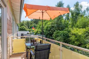 a patio table with an umbrella on a balcony at Ferienwohnung "Beim Tannenbaum" in Reichensachsen
