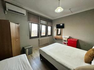 a bedroom with two beds and a television and windows at Biter Hotel in Istanbul