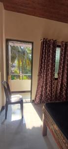 a bedroom with a chair and a bed and a window at Serina Guest House Malvan in Malvan