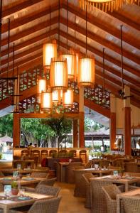 a dining room with tables and chairs and chandeliers at Bluewater Maribago Beach Resort in Mactan