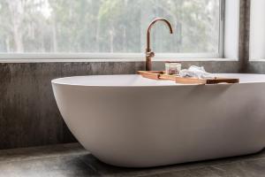 a white bath tub in a bathroom with a window at The Woods Pokolbin in Pokolbin +286 photos