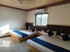 a bedroom with two beds and a window at Patidar Villa Mount Abu in Mount Ābu