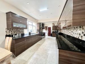 a large kitchen with wooden cabinets and tile floors at Spacious Double Room In Central Stoke in Stoke on Trent