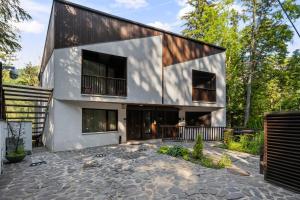 a house in the woods with a stone patio at Drago Chalet Sinaia, hot tub and sauna in Sinaia