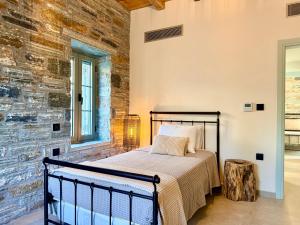 a bedroom with a bed in a room with a stone wall at Agnandio Retreat Euboea in Animborió