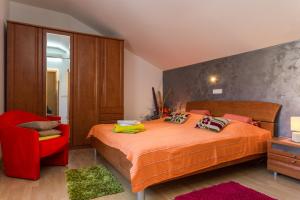 a bedroom with a bed and a red chair at Guesthouse Ivona in Dubrovnik