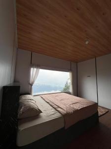 a bedroom with a large bed with a window at Numaya Glamping Type BOX in Garung