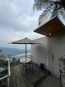 a patio with a table and an umbrella on a deck at Numaya Glamping Type BOX in Garung