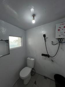 a white bathroom with a toilet and a window at Numaya Glamping Type BOX in Garung