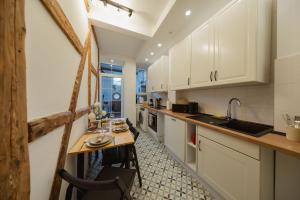 a kitchen with white cabinets and a wooden table at HYGGE HOMES - Apartment 'gamleby' in Lüneburg