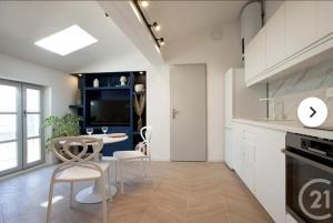 a kitchen with white cabinets and a table and chairs at Cocon Voltaire - Arles centre historique in Arles