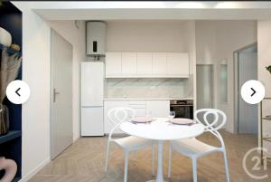 a white kitchen with a white table and chairs at Cocon Voltaire - Arles centre historique in Arles