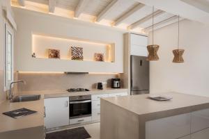 a kitchen with white cabinets and a counter top at Andros Royal Villa in Koumárion