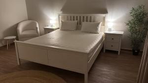 a bedroom with a large white bed and a chair at فيلا الريف in Kusāt