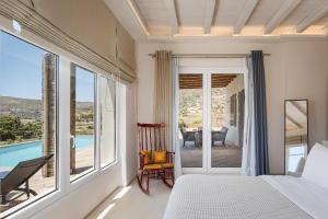 a bedroom with a bed and a balcony with a pool at Andros Royal Villa in Koumárion +58 photos