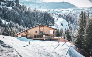 a man is skiing down a snow covered slope in front of a lodge at Hôtel LAPIAZ & Spa - FLAINE in Flaine