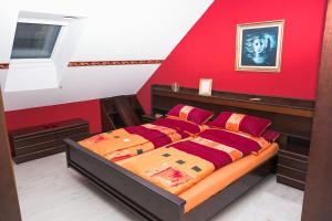 a bedroom with a bed with a red wall at Ferienwohnung Rebekka in Riedlingsdorf