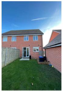 a red brick house with a fence and a yard at Aries de Baldock in Canterbury