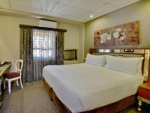 ein Schlafzimmer mit einem großen weißen Bett und einem Schreibtisch in der Unterkunft ANEW Hotel Hatfield Pretoria in Pretoria