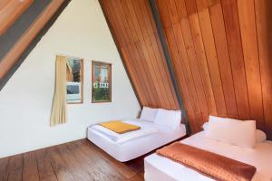 two beds in a room with wooden walls at Villa Platinum 2 in Banjarnegara