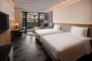 a hotel room with two beds and a television at Bristoria Hotel Yangzhou in Yangzhou