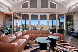 a living room with a brown leather couch and tables at Lakeside Serenity in Hindmarsh Island
