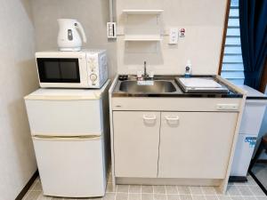 a small kitchen with a sink and a microwave at Eight One in Osaka