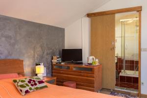 a bedroom with a bed and a dresser with a television at Guesthouse Ivona in Dubrovnik