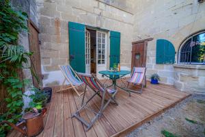 a patio with a table and chairs on a wooden deck at Castel La Fabrik'Créative in Saint-Barthélémy-dʼAgenais