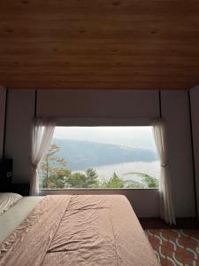 a bedroom with a large window with a bed at Numaya Glamping Type BOX in Garung