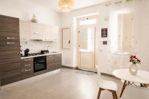 a kitchen with wooden cabinets and a table and a table and chairs at Maison Alexeur - Intero Appartamento in Crotone