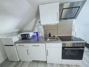 a white kitchen with a sink and a microwave at Unterkunft in Eggenfelden in Eggenfelden +5 photos