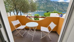a table and chairs on a balcony with a view of the water at Xigga apartments in Donji Stoliv