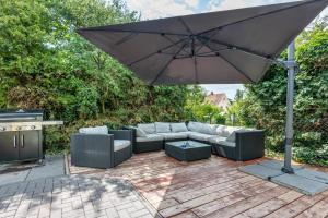 a patio with an umbrella and couches and a grill at Geräumiges Haus mit Garten Terasse in Nuremberg