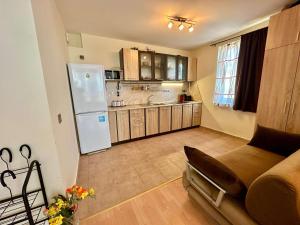 a kitchen with a white refrigerator and wooden cabinets at Cozy Corner Studio in Crown Fort in Sveti Vlas