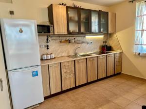 a kitchen with a white refrigerator and wooden cabinets at Cozy Corner Studio in Crown Fort in Sveti Vlas +19 photos