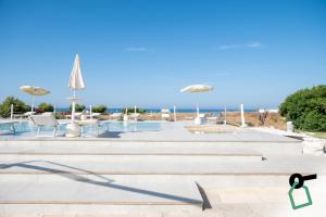 a pool with chairs and umbrellas on the beach at Hotiday Fasano Mare in Savelletri di Fasano