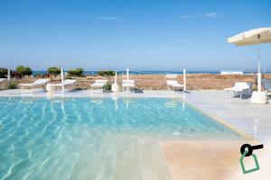 a large swimming pool with chairs and an umbrella at Hotiday Fasano Mare in Savelletri di Fasano