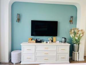 a white dresser with a tv on a blue wall at Ocean Homes cơ sở SH24 in Ðình Loan