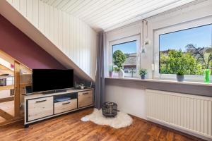 a living room with a tv and two windows at Ferienwohnung an der Bieke in Olsberg