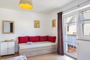 a room with a couch with red pillows and a window at Die Gemütliche Fewo in Breitenberg