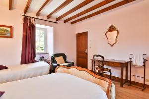 a bedroom with two beds and a desk and a desk at Manoir De Labelangerie in Acqueville