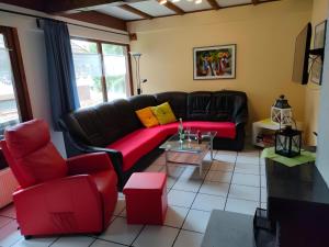 a living room with a black leather couch and red chairs at Ferienhaus Tindy am Silbersee in Frielendorf