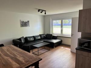 a living room with a black leather couch and a table at Hochwertige Monteurunterkunft in Zarrentin