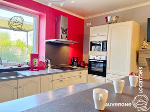 a kitchen with red walls and a counter top at Le Chardonneret du Sancy in Montaigut-le-Blanc