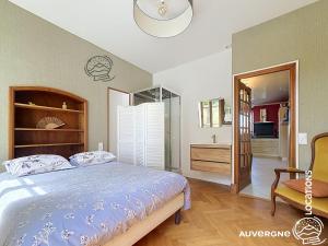 a bedroom with a bed and a chair at Le Chardonneret du Sancy in Montaigut-le-Blanc